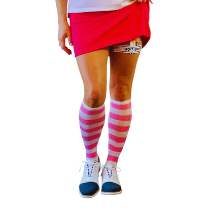 A woman in a pink skirt wearing the golf garter accessory. This image is taken from the front.